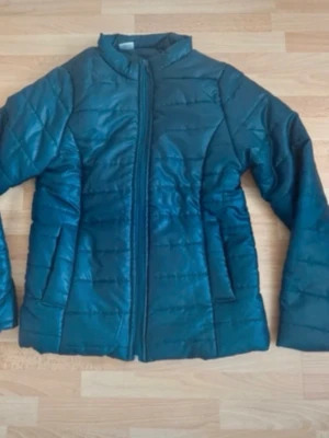 Ny. Mörkblå pufferjacka med dragkedja - Snygg mörkblå pufferjacka med quiltad design och hög krage. Jackan har två sidofickor och stängs med dragkedja framtill. Perfekt för kalla dagar och ger en stilren look. Materialet är syntetiskt och jackan har en klassisk passform.
