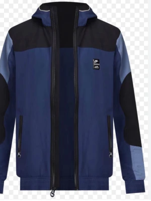 Blå och svart Nike vindjacka - Snygg vindjacka från Nike i blått och svart med dragkedja framtill och två fickor med dragkedja. Jackan har huva och coola färgblock på ärmarna. Perfekt för dig som vill ha en sportig och trendig look. Materialet är lätt och vindtätt.