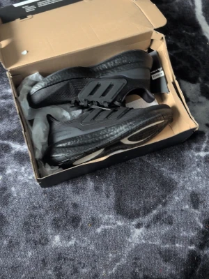 Svarta Adidas sneakers sprillans nya - Säljer ett par helsvarta, testade 1 gång inomhus,  Adidas sneakers med mesh- och syntetmaterial, klassisk tre-randig design på sidan och tjock, dämpad sula. Skorna har snörning och låg profil, perfekta för en sportig och stilren look.