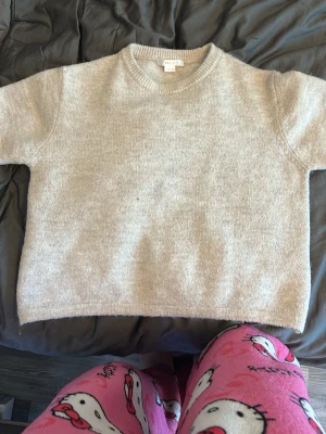 Beige stickad tröja Gina Tricot - Mysig beige stickad tröja från Gina Tricot med rund halsringning och ribbade muddar. Tröjan har en enkel och stilren design som passar perfekt till höst och vinter. Materialet känns mjukt och skönt mot huden.