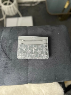 Grå kortfodral från Goyar - Snyggt grått kortfodral från Goyar med det klassiska mönstret i vitt. Fodralet har flera fack för kort och är gjort i slätt läder och canvas. Perfekt för dig som vill ha en stilren och exklusiv accessoar i fickan.
