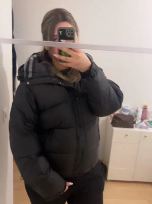 svart burberry puffer - Säljer en svart burberry pufferjacka med huva och rutigt innerfoder. Jackan har dragkedja och knappar framtill samt två sidofickor med dragkedja. Perfekt för kalla vinterdagar och riktigt skön att bära. Oversized passform för en avslappnad look. Priset kan diskuteras så passa på🦦