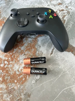 Svart Xbox trådlös handkontroll - Säljer en svart trådlös Xbox-handkontroll med klassisk layout och färgade knappar (X, Y, A, B). Ergonomisk design med greppvänliga handtag. Passar perfekt för gaming på Xbox eller PC. Batterifack på baksidan, drivs av AA-batterier (medföljer).