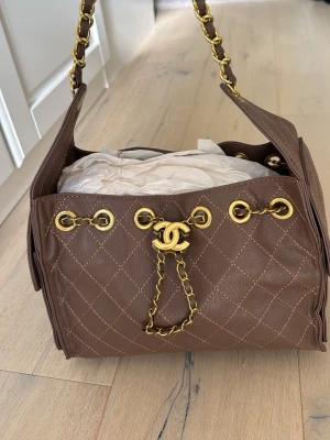CC väska  - Säljer en superfin cc monogram väska med guldiga detaljer, den är brun med ett speciellt mönster, den lilla modellen