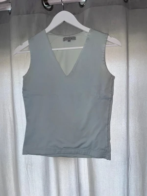 Vit ärmlös topp från Vila - Snygg ljusgrå topp från Vila med v-ringning och ärmlös design. Perfekt att matcha med jeans eller kjol för en clean och enkel look. Tillverkad i mjukt material som känns skönt mot huden.