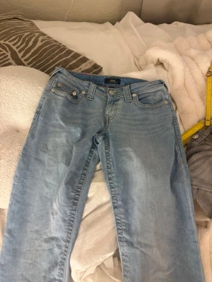 Truereligon baggy jeans - Säljer ett par ljusblå true religon jeans med rak passform och klassisk femficksdesign. Användt en gång! Jeansen har normal midja och stängs med knapp och dragkedja. Perfekta för en avslappnad och trendig look.