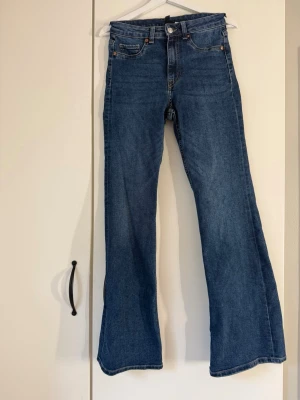 Blå bootcut jeans med hög midja - Säljer ett par klassiska blå bootcut jeans med hög midja och fem fickor. Jeansen har en snygg tvätt och vida ben som ger en retrovibe. Tillverkade i denim med stretch. Från H&M i strl 38🌸