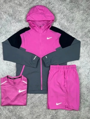 Nike träningsset rosa och grå - Snyggt träningsset från Nike med hoodie, t-shirt och shorts. Setet är i rosa och grått med svarta detaljer och vita Nike-loggor. Hoodien har dragkedja och huva, shortsen har resår i midjan och t-shirten är kortärmad. Perfekt för träning eller sport.