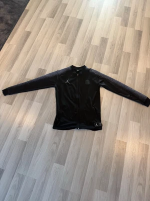 Svart psg x Jordan collab - Säljer en snygg svart Jordan x PSG ziptröja. Använd få gånger och i mycket fint skick, inga hål eller fläckar. Perfekt till både träning och vardag.