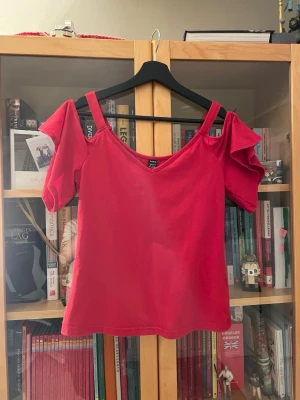 Röd offshoulder topp med volang - Snygg röd topp med offshoulder-design och breda axelband. Toppen har volangdetaljer på ärmarna och en v-ringad halsringning. Perfekt för dig som vill sticka ut med en färgstark och trendig look.Röd off shoulder topp - Jättesöt topp i strl M - köpt från Shein och är använd men i fint skick. 