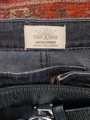 Grå slim fit jeans med tvättad look från Jack & Jones  - Snygga grå slim fit jeans med tvättad effekt och klassisk femficksdesign. Jeansen har svarta sömmar och metallknappar. Passformen är smal och benen är raka. Perfekta för en avslappnad och trendig stil. Helt nya jeans från Jack, köpte de från Websidan. Tyvärr de va för små för mig och  jag han inte lämna tillbaks de i tid. 