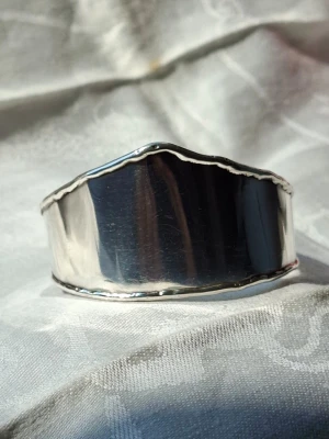 Edgy/boho handcuff i silver - Retrosmycke från 1990-talet, handmade I Danmark. Snygg detalj särskilt för den som gillar boho, vintage, gott, futurism eller edgy mode. Omkrets 18 cm. Några mycket ytliga repor som bara syns på mycket nära håll. Blekhetstest visar grått med dragning åt svart och lukttest ger inga koppar/mässingslukter, vilket innebär en finhet över 800. Har du frågor är det bara att messa mig.