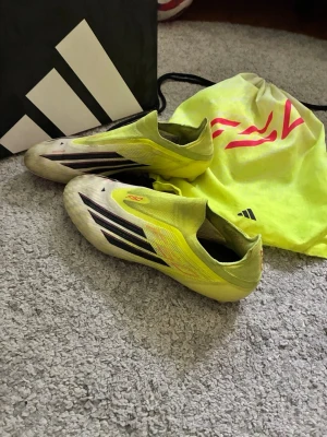 Gula Adidas X Speedflow fotbollsskor elite  - Säljer ett par gula Adidas X Speedflow fotbollsskor med svarta och röda detaljer. Skorna har låg profil, strumpliknande passform och är tillverkade i lätt syntetmaterial. Sulan har fasta dobbar för spel på naturgräs. Perfekta för dig som vill ha speed på planen. Skriv om du har några frågor om skorna 