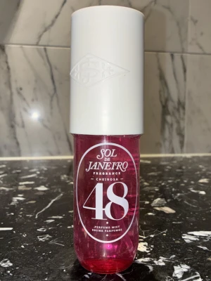 Sol de Janeiro Cheirosa 48 Parfymmist - En snygg parfymmist från Sol de Janeiro i modellen Cheirosa 48. Flaskan är genomskinlig rosa med en stor vit kork och har en modern, rundad form. Perfekt att ha med i väskan för en fräsch doft när som helst.