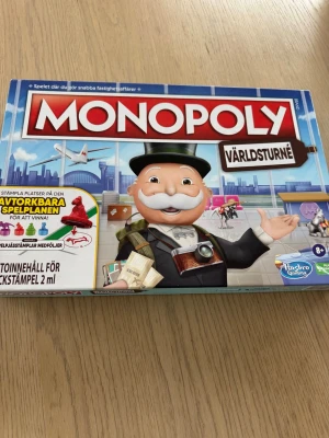 Monopoly Världsturné brädspel - Monopoly Världsturné är ett brädspel med färgglada spelpjäser, tärningar, spelkort och sedlar i olika valörer. Lådan är blå med tydlig grafik och spelet innehåller plast, papper och kartong. Perfekt för spelkvällar med vänner eller familj.