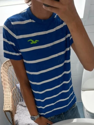 Hollister Randig T-Shirt ~ Vintage - Vintage Hollister Randig T-Shirt | Storlek: L men sitter som M | Passform: Normal Fit | Färg: Blå/Vit Randig | 100% Cotton | Skick: 9/10 Inga defekter | Pris ej hugget i sten!