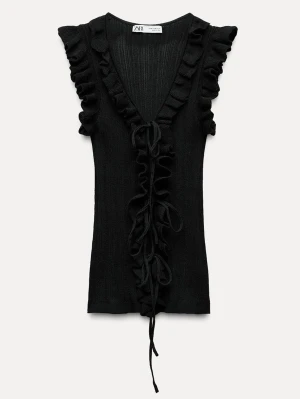 Svart ribbad topp med volang och knyt - Snygg svart ribbad topp med djup v-ringning, volangdetaljer längs axlar och framkant samt knyt framtill. Ärmlös design som ger en trendig och ungdomlig look. Perfekt att styla med jeans eller kjol för en cool outfit.