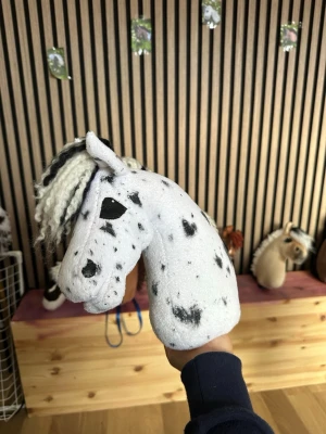 Explotion spotti - Unik käpphäst med vit bas och svarta prickar, samt svart och vit man i garn. Hästhuvudet är mjukt och detaljerat, perfekt för lek och fantasi. Passar dig som gillar hästar och vill ha något personlig till samlingen.gjord av explotion på Instagram som är en känd käpphäst skapare.
