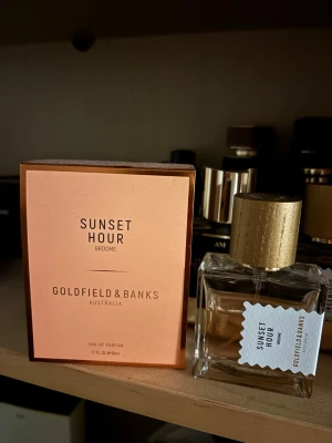 Sunset Hour parfym Goldfield & Banks - Sunset Hour från Goldfield & Banks är en exklusiv parfym i en elegant, fyrkantig glasflaska med guldfärgat lock. Doften kommer i en stilren förpackning i persikoton. Perfekt för dig som vill ha en unik och lyxig signaturdoft.