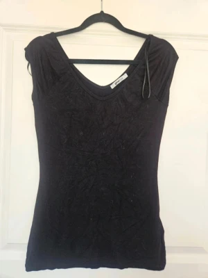 Topp  Gina Tricot L - En enkel och stilren svart topp från Gina Tricot. Toppen har v-ringad hals både fram och bak, ärmlös design och är gjord i mjuk bomullsmix. Perfekt att matcha med jeans eller kjol för en clean look.  Kan även hämtas I Partille  E5