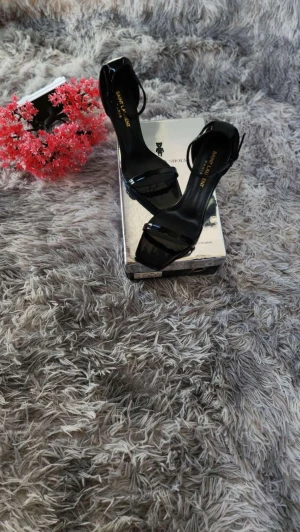 Svarta klackar - Snygga svarta klackar med smala remmar och fyrkantig tå. Skorna har hög klack och är tillverkade i glansigt skinn. Guldiga YSL-detaljer på hälen ger en lyxig touch. Perfekta för dig som vill sticka ut med stilrena och eleganta skor.