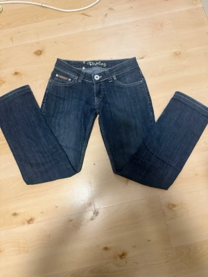 Mörkblå jeans från Replay - Snygga mörkblå jeans från Replay med raka ben och dekorativa sömmar på bakfickorna. Klassisk femficksmodell med silverfärgade nitar och logopatch bak i midjan. Tillverkade i slitstark denim med en cool tvätt.
