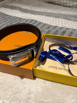 Svart Louis Vuitton bälte i skinn - Snyggt svart bälte från Louis Vuitton i skinn med klassiskt spänne. Kommer i originalförpackning med dustbag och blått band. Perfekt accessoar för att lyfta din outfit med en exklusiv touch. Helt oanvänd och redo att fraktas. Pris går att diskuteras vid snabb affär!🫡