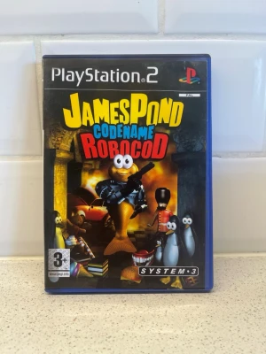 James Pond Codename Robocod PS2 spel - James Pond Codename Robocod till PlayStation 2. Plattformsspel med färgglad tecknad grafik och humoristisk stil. Omslaget är blått med spelets logga i gult, blått och rött. Perfekt för dig som gillar retro och klassiska äventyrsspel. Fungerar toppen!