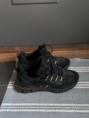 Svarta sneakers från Cruyff  - Snygga svarta sneakers från Cruyff med robust sula och mesh- samt mockadetaljer. Skorna har svarta och vita snören och coola detaljer längs sidan. Märket Cruyff syns på hälen. Perfekta för dig som gillar streetwear och chunky stil.