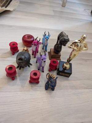Samling figurer och statyetter - Säljer en samling med olika figurer: tre färgglada rådjur i rosa, blått och lila, en svart fågel, en blå drake som nyckelring, en lejonkulptur i mörkt material och en guldig Oscars statyett samt glas dekoratioer i limited edition.Samt ett smyckespaket med blandade vintage armband, halsband och örhängen i silverfärg och pärlor. Innehåller chunky kedjor, vita pärlor och svarta detaljer. Kommer i en cool svart keramiksko med en vit katt på kanten. Perfekt för dig som gillar dekorationer eller samla