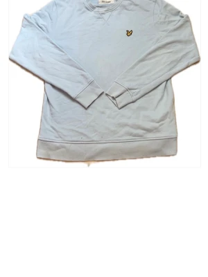 Ljusblå sweatshirt från Lyle & Scott - Ljusblå sweatshirt från Lyle & Scott i mjuk bomull. Klassisk rund halsringning, ribbade muddar och den ikoniska gula örnloggan broderad på bröstet. Enkel och stilren design som passar till det mesta.