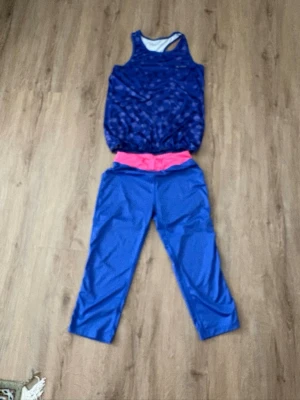 Blått träningsset från SOC - Säljer ett sportigt träningsset från SOC med blått linne i prickigt mönster och matchande blå träningsbyxor med bred rosa midjeresår. Perfekt för gymmet eller löprundan. Materialet är stretchigt och andas, vilket gör det bekvämt under träning. Kolla gärna mina andra annonser❗️