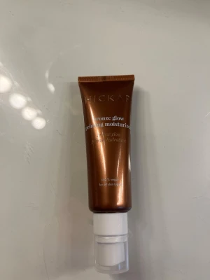 Bronze glow priming moisturizer - Bronze glow priming moisturizer i en snygg bronsfärgad tub med pump. Ger huden en fräsch glow och fungerar både som primer och återfuktande kräm. Tuben är smidig att använda och passar alla hudtyper. 100% vegansk formula.