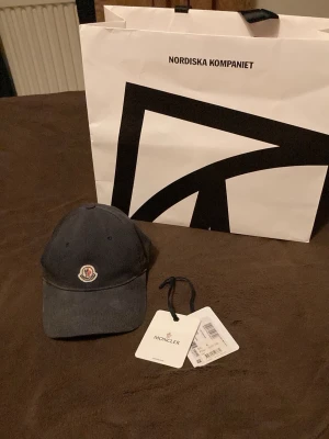 Mörkblå Moncler keps  - Köpt på NK i Göteborg för något år sedan. Jag kan sänka priset vid snabb affär eller om du vill köpa fler kläder. Den är rätt så missfärgad men det kan vara snyggt. 