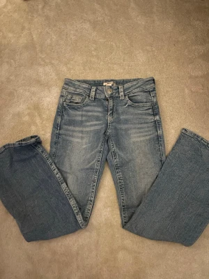 Ljusblå bootcut jeans med broderi - Säljer ett par ljusblå bootcut jeans med snygga broderade bakfickor och ficklock med knapp. Jeansen har låg midja och klassisk femficksdesign. Har bara andvänds 1 eller 2 gånger max och jag säljer pågrund av att dom inte passar mig särskilt bra. Jeansen är ljusare än på bilden eftersom att det är mörkt ljus. Skriv om ni har några frågor. 