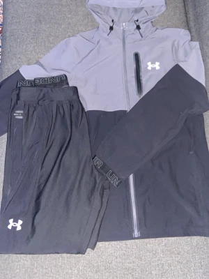 Under Armour träningsset svart/grå - Svart grått under armour tracksuit ifrån JD i storlek S. Pris kan diskuteras. Byxorna är i M men sitter som S. Perfekt året om. Kan lösa fler bilder om du vill ha. Mvh Wilmer🙏🫶