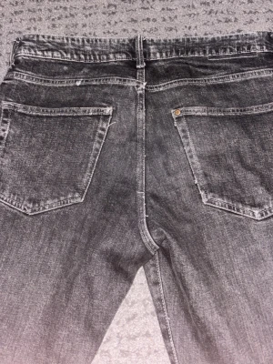 Grå regular fit jeans - Säljer ett par grå regular fit jeans med raka ben och klassiska bakfickor. Jeansen har en tvättad look och är tillverkade i denim. Perfekta för en avslappnad och trendig stil. Dem har några år på nacken och därför fått snygga slitningar samt bra tvätt👍🏼 storlek 31/32
