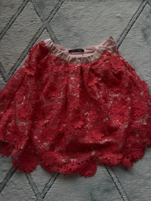 Rosa blommig kjol str 134/140 - Söt rosa kjol med blommig och transparenta partier. Kjolen har en lös passform och fina volangdetaljer längs kanterna. Perfekt för flika som vill ha en super snygg kjiol med unika detaljer. Str 134/140