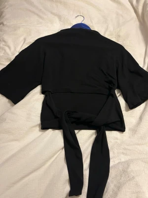 Svart T-shirt med knytband - Snygg svart T-shirt knytband i ryggen och vida, korta ärmar. Från Gina Tricot i storlek M, använd fåtal gånger 