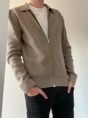 Beige fullzip - Tjena👋 Säljer denna stilren beige fullzip med klassisk krage och långa ärmar från Jack & Jones i storlek S🤩 Tröjan har en rak passform och är tillverkad i ett mjukt, stickat material som känns skönt mot huden😌 Perfekt att bära över en t-shirt för en avslappnad look💸 Meddela gärna vid frågor📩