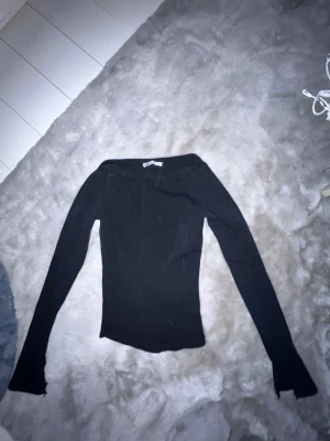 Svart långärmad topp från Zara - Säljer en svart långärmad topp från Zara. Toppen har en tight passform och är tillverkad i ett mjukt, stretchigt material som sitter snyggt på kroppen. Perfekt att styla med jeans eller kjol för en clean look.