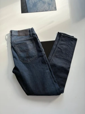 Mörkblå raka jeans - Snygga mörkblå jeans med rak passform och klassisk femficksdesign. Jeansen har en diskret tvättad look och detaljer som bälteshällor och knappgylf. Perfekta till en avslappnad stil och funkar året runt.