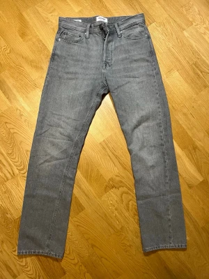 Grå  jeans Jack & Jones - Säljer ett par sköna gråa relaxed fit jeans från Jack & Jones, modell Chris med storleken w29/L32. Klassisk femficksdesign och raka ben. Perfekta för en chill och avslappnad stil. Materialet är mjukt denim i bomull som känns skönt hela dagen. Vid frågor, extra bilder eller liknande är det bara att kontakta mig!