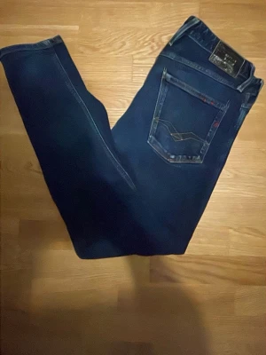 Blå Replay Anbass - Snygga mörkblå jeans från replay. Ny pris 1100kr. Den ena fickan har också ett litet hål. Kan sänka priset lite om det behövs.
