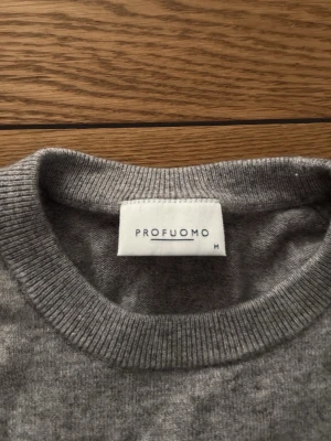Grå tröja från Profuomo - Klassisk grå tröja från Profuomo i storlek M. Tröjan har rund halsringning och är tillverkad i ett mjukt material som passar perfekt nu till hösten. Enkel och stilren design som funkar till många olika outfits. Storleken är M men passar nästan bättre som en storlek S. Säljer då den blivit för liten. Skriv gärna om du har frågor!