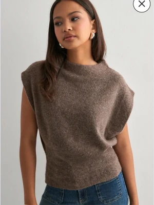 Brun ärmlös stickad topp - Säljer en brun stickad topp med korta ärmar och hög hals. Materialet är mjukt och fluffigt, perfekt för lager-på-lager. Passar till jeans eller kjol för en chill look. Enkel och stilren design utan synliga detaljer eller mönster. Har samma i xs så skriv om du är intresserad 