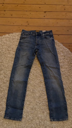 Ljusblå Slim jeans från Jack & Jones - Ljusblå jeans från Jack & Jones med raka ben och klassisk femficksdesign. Jeansen har en snygg tvättad look med slitningar och är tillverkade i bomullsdenim. Perfekta för en avslappnad och trendig stil. Passform slim