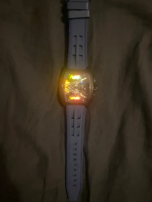 Unik Skeleton-klocka med blått silikonarmband – Oanvänd! - Säljer en riktigt fet klocka i helt oanvänt skick. Den har en tuff skeleton-design där man ser urverket, och ett sjukt snyggt hologram-aktigt glas som skiftar färg i ljuset (se bilder!). Det sitter ett bekvämt och sportigt blått silikonarmband på. Klockan har även lysande detaljer som syns tydligt i mörkret (se sista bilden). Riktigt unik design som garanterat drar blickarna till sig. Den är endast uttagen för fotografering och har fortfarande skyddsplasten kvar på baksidan. Allt funkar.