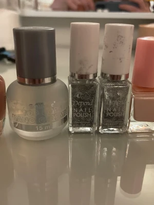 Silverglittrigt nagellack från Depend - Två flaskor nagellack från Depend i silverglittrig nyans. Kommer i fyrkantiga flaskor med vita lock. Perfekt för dig som vill ha extra glitter på naglarna och skapa en festlig look. Lacket har en intensiv glans och små glitterpartiklar. Sedan en liten mattare färg som är till vänster och även en genomskinligt nagellack som gör att det håller längre. Och till sist så finns det en ljusrosa färg med lite glitter som är super fin färg! 