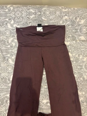 Bruna mjuka loungewear-byxor - Ett par bruna loungewear-byxor i mjukt och stretchigt material. Byxorna har en bred linning upptill och raka ben, perfekta för att chilla hemma eller mysa runt i. Färgen är en djup brun och passformen är avslappnad.